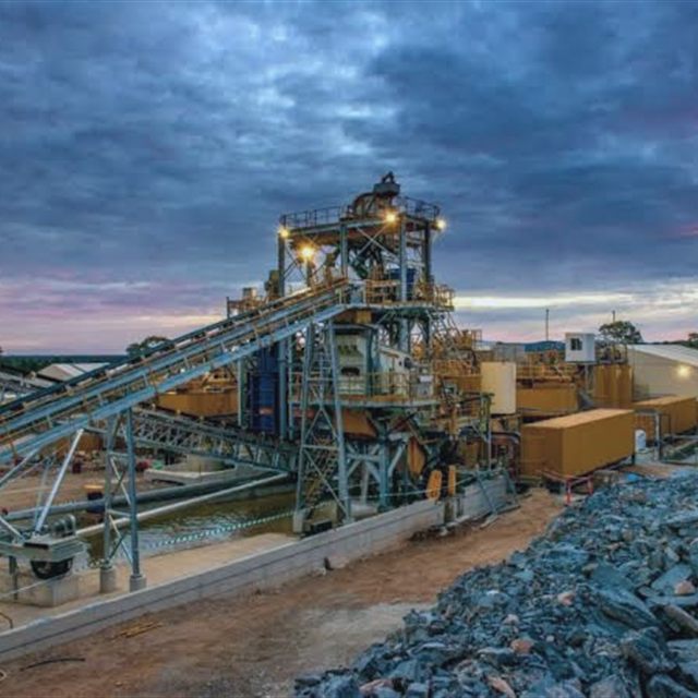Planta de beneficiamento de minério com correias transportadoras ao entardecer