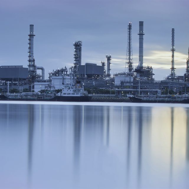 Planta petroquímica refletida na água sob céu azul